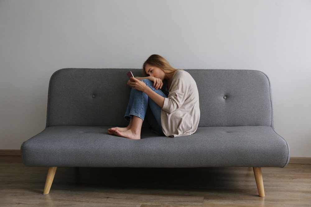 a woman sitting on a couch looking at a phone