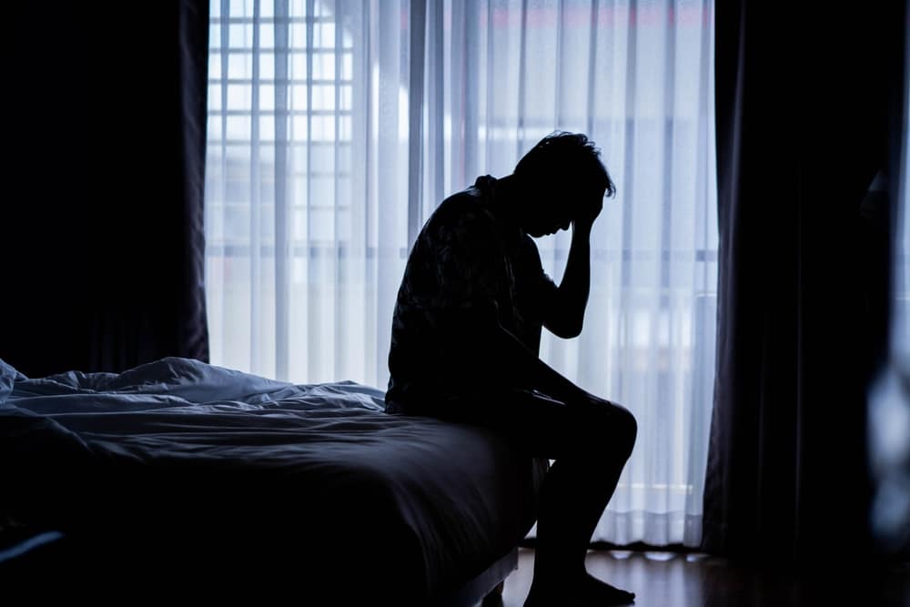 a silhouette of a man sitting on a bed